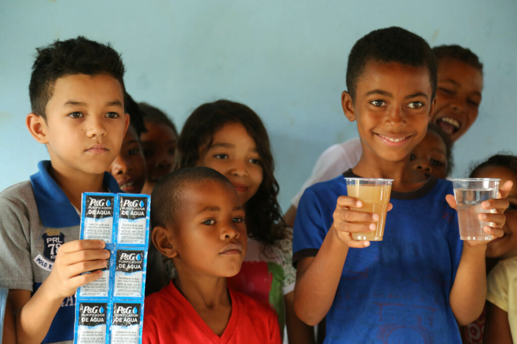 Crianças em Chapada do Norte atendidas pelo programa. Os copos mostram o "antes" e o "depois" do uso do sachê. Foto: Jorge Novais/ Caixa Alta