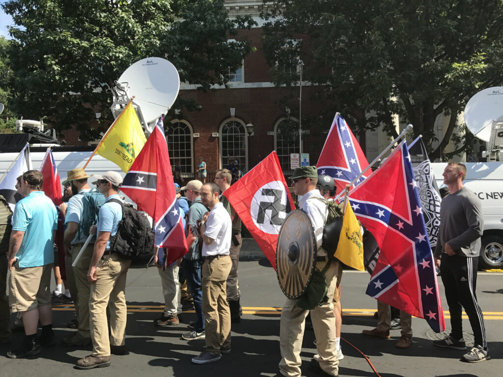 A bandeira nazista exibida junto com a bandeira da Confederação durante a marcha Unite the Right em Charlottesville (crédito: Anthony Crider/Flickr - CC BY 2.0)
